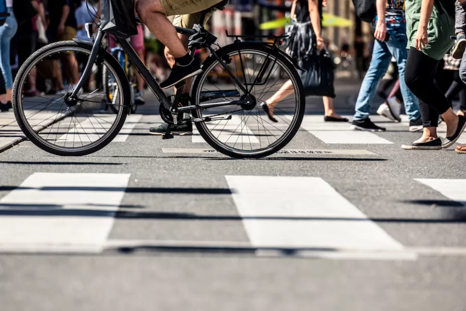Low shot of pedestrians and a bike crossing a striped crosswalk.