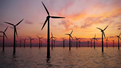 Offshore wind turbines in water against a sunset sky