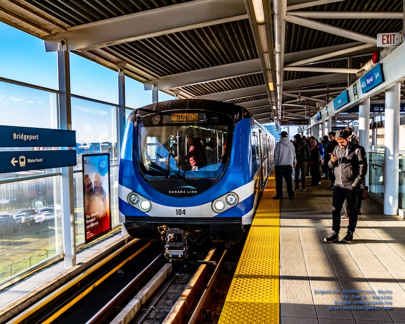 Vancouver light rail train at station with platform crowded with people.