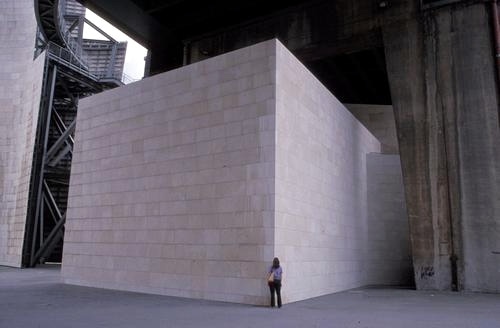 Massive blank stone cube with person standing next to it