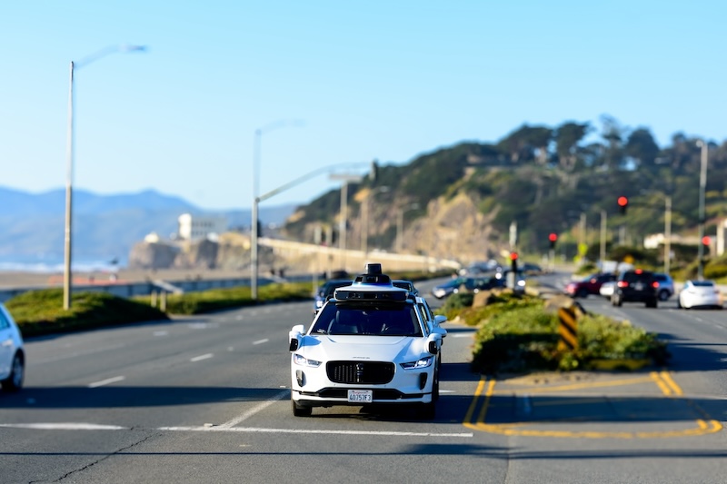 White Waymo self-driving car on Great Highway coastal road in San Francisco, California.