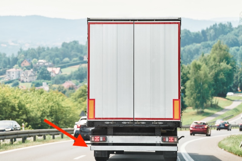 View from back of white tractor trailer on road with rear underride  guards