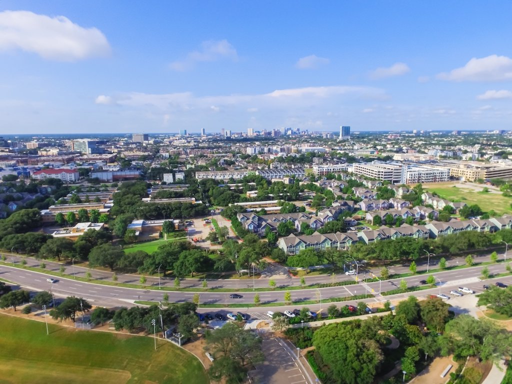 Aerial view of low-rise housing in Houston, Texas with taller buildings in background.