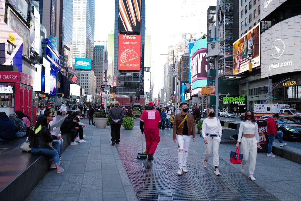 People walking in Times Square, New York City after Covid, most wearing masks.