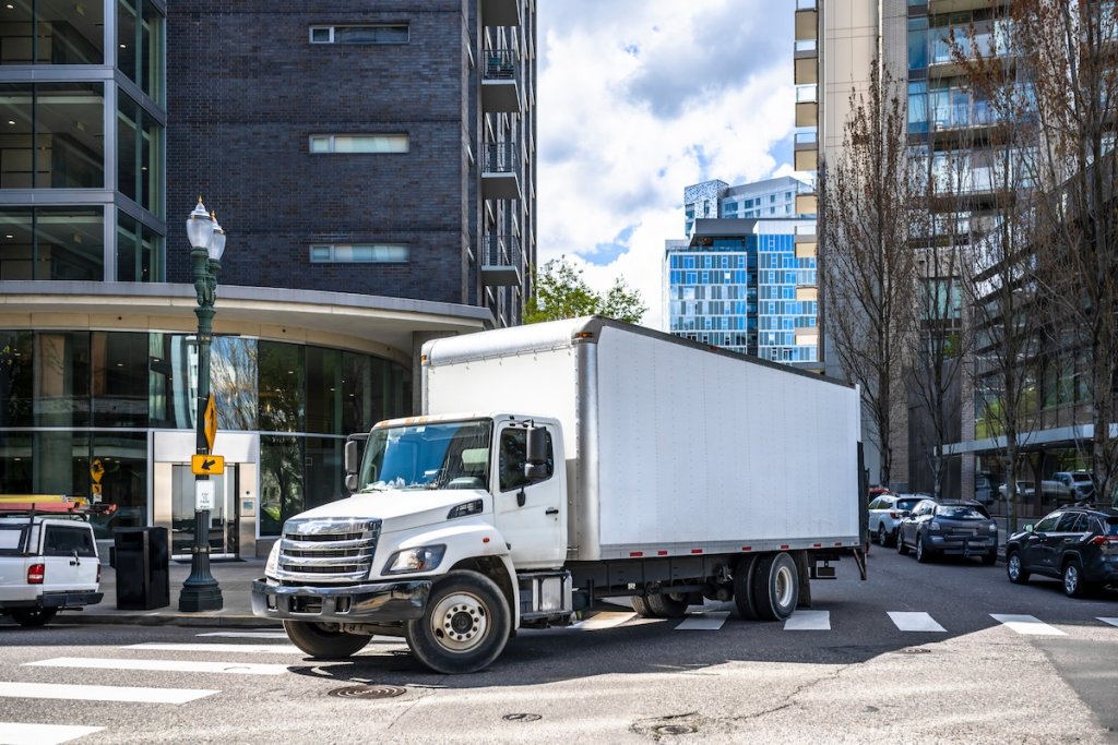 White big rig truck on city street turning corner.