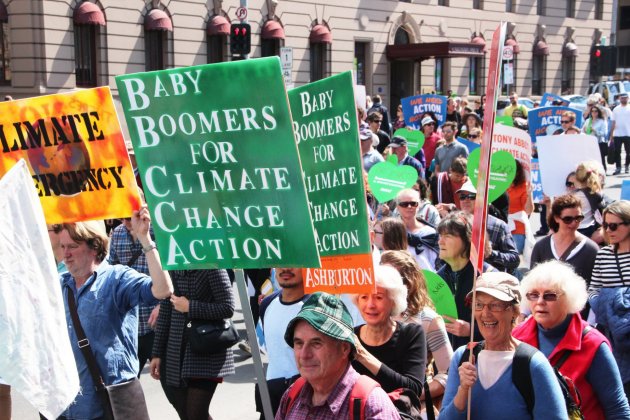 Protestors march to fight climate change. Two of the signs held by the marchers read, "baby Boomers for Climate Change Action."