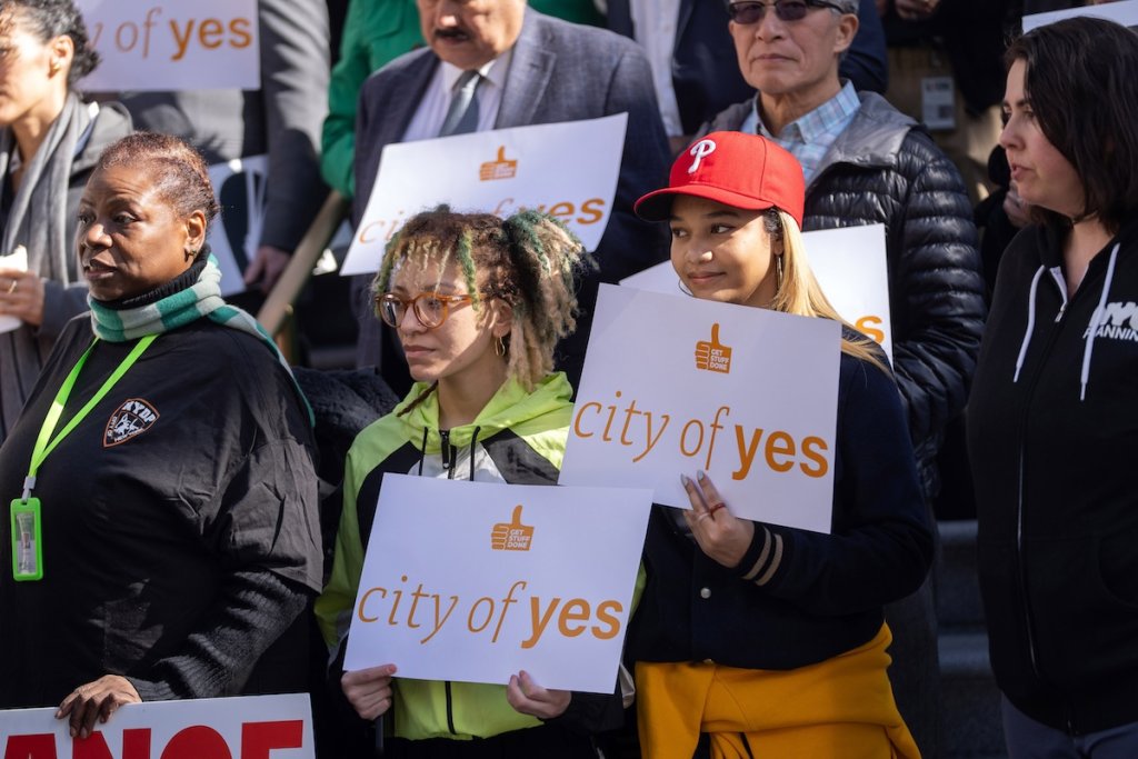 Crowd holding signs supporting NYC City of Yes zoning reform.
