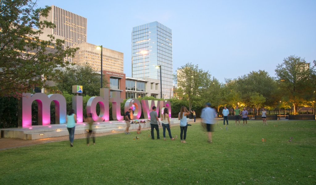 A sign reading Midtown provides the backdrop for a game with numerous participants.