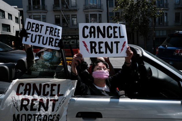 Protestors wearing masks during the Covid-19 pandemic wave signs from a car that read "Cancel Rent."