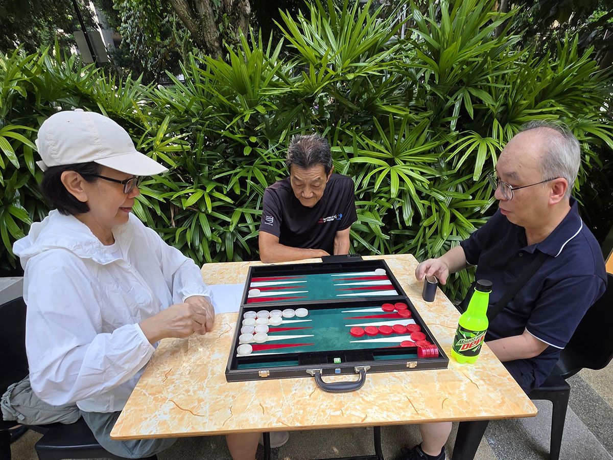 Three people play backgammon together.