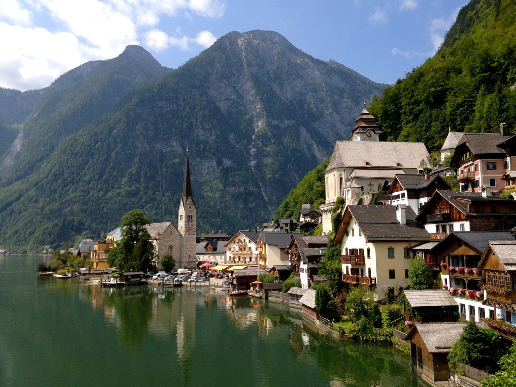 A pictureseque European villiage on the egdge of a lake surrounded by mountains.