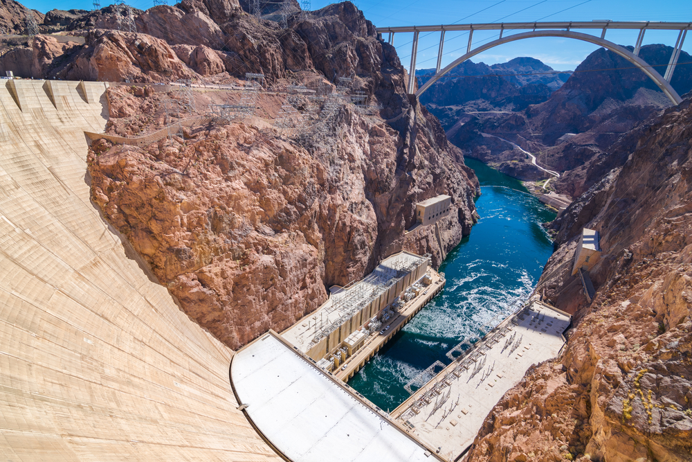 A picture downriver of the Hoover Dam, with a bridge and the dam’s power generating station visible below.