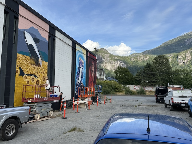 Murals on garage doors inSquamish, BC with rocky mountains visible in background.