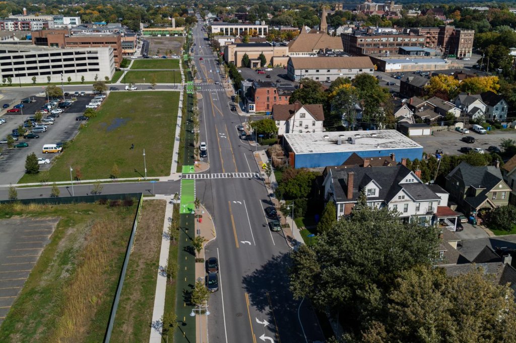 A aerial photo of an urban street in Rochester, New York, with a green protected bike lane running alongside. 
