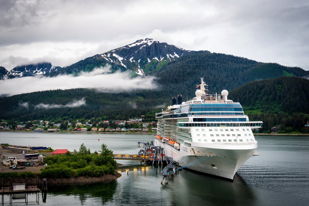 A cruise-ship sits in port with a snowy mountain in the background.