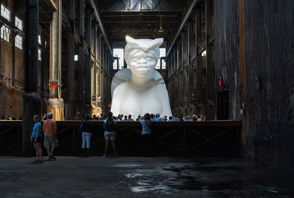 Sphinx-like sculpture with African features looms over visitors inside empty Domino Sugar Factory