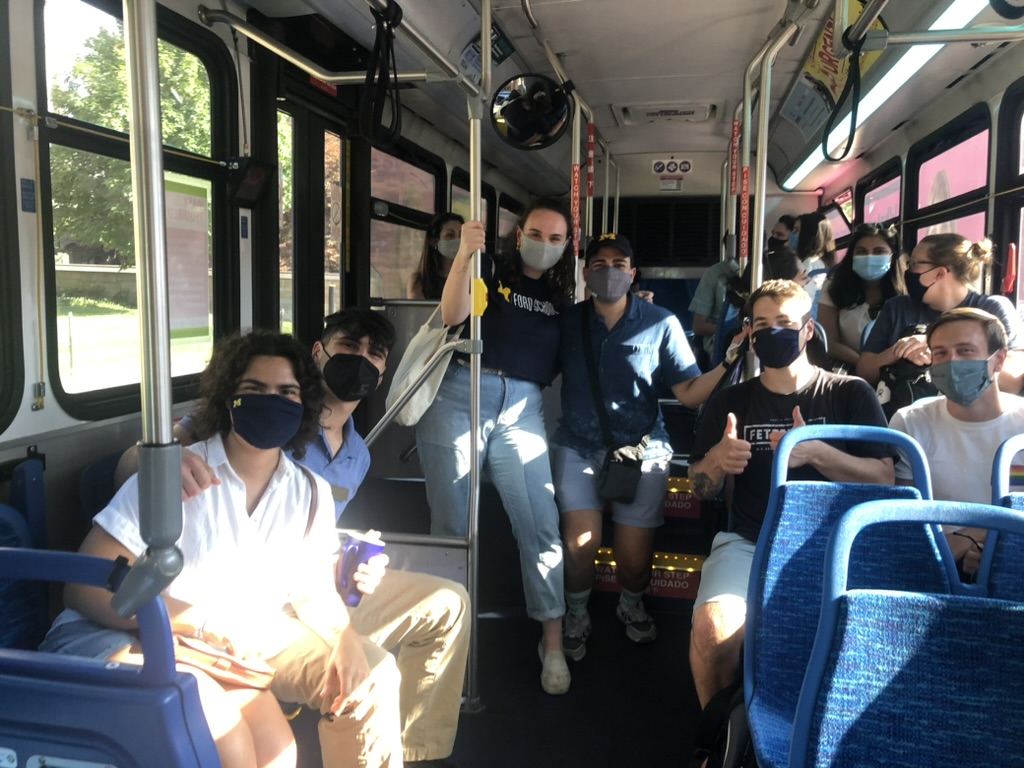 Grad students on a bus smiling for photo wearing masks during Covid.