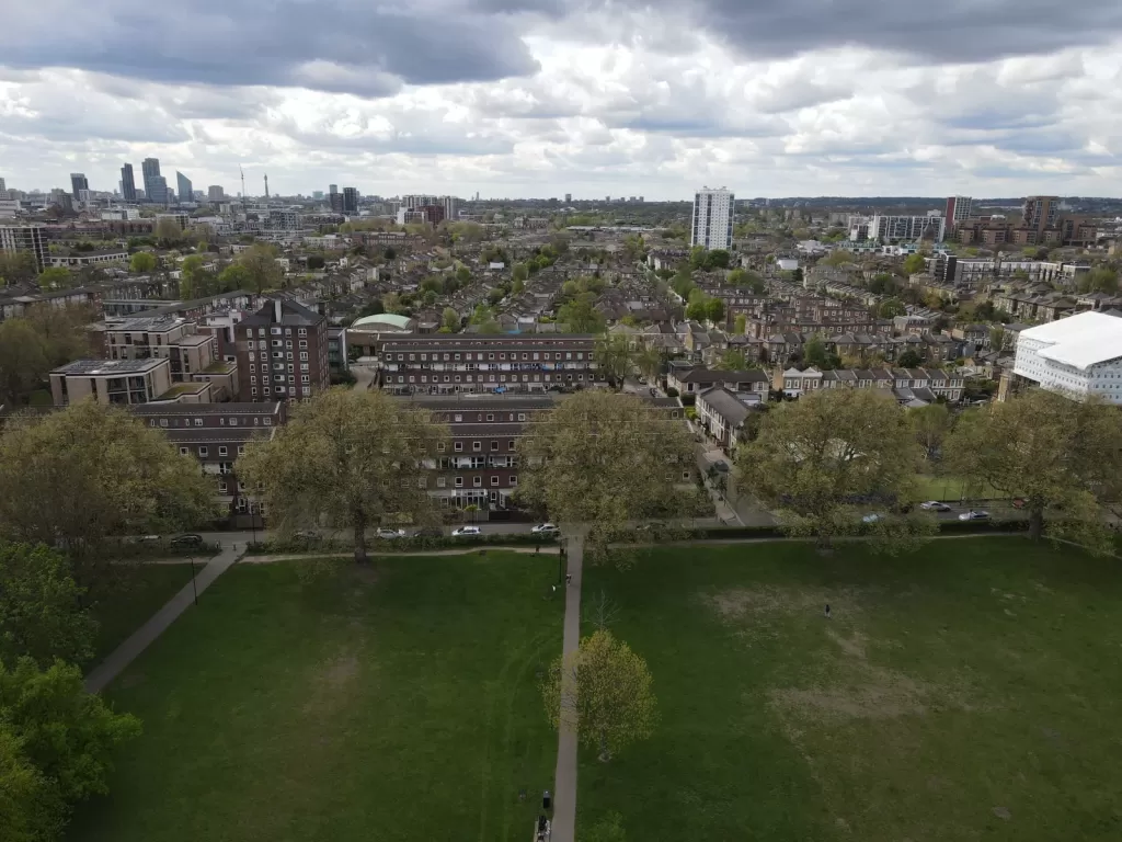Birds-eye view of park separated from city beyond by a road.