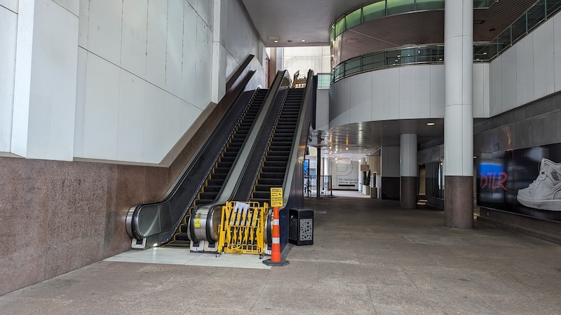 Empty escalator with one side blocked off with yellow barrier.