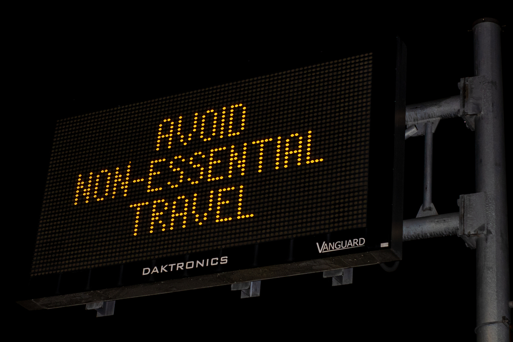 An electronic street sign reads "Avoid Non-Essential Travel," referencing the stay-at-home orders of the early Covid-19 pandemic.