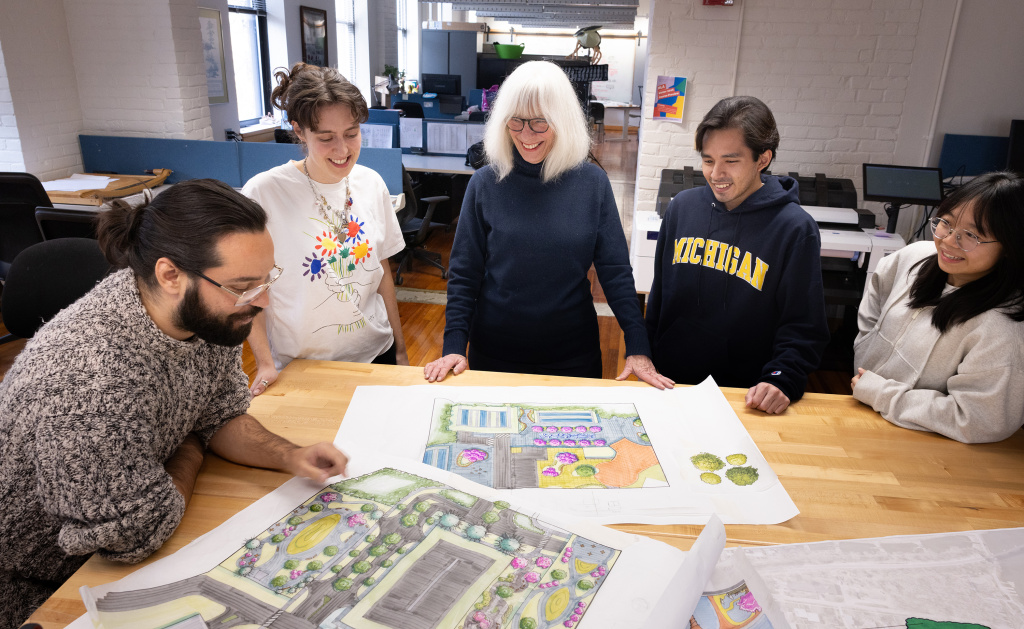 Image of a small class standing around mapped out diagrams