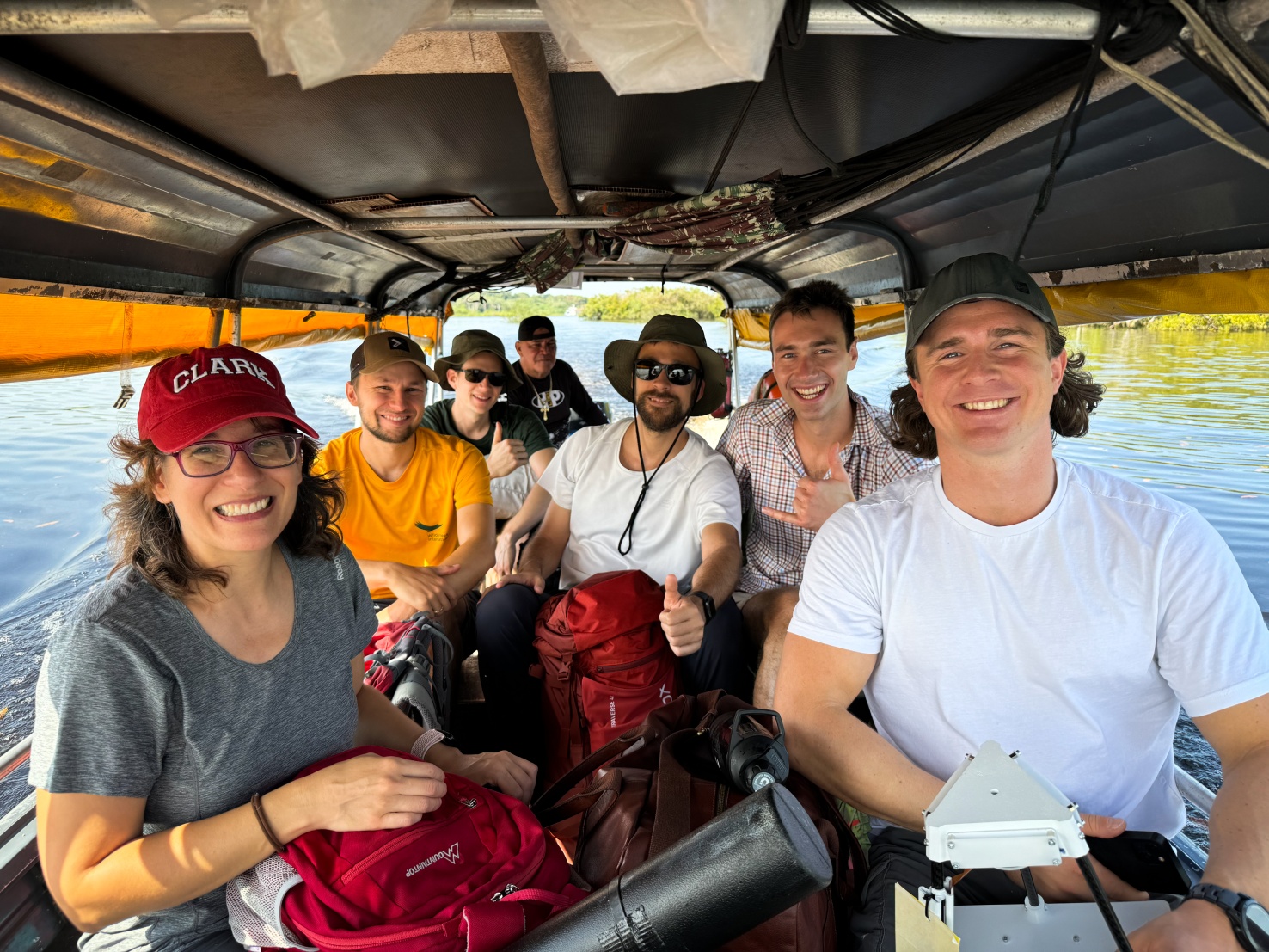 Smiling Clark University students smiling in photo of them in a small boat over a river