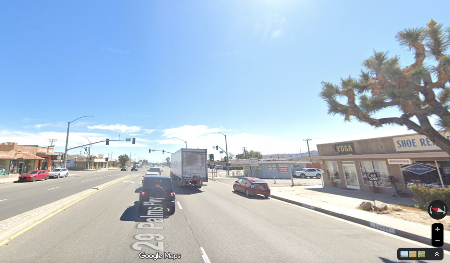 A wide street with a big sunny sky and short buildings in the desert