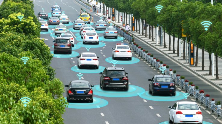 A conceptual image showing a group of vehicles with computer generated signals emanating from beneath the cars. A system of coordinated self-driving vehicles is implied.