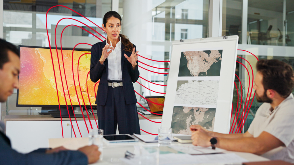 Women presenting a map of North America on her left side with a monitor displaying heat maps of North America behind her