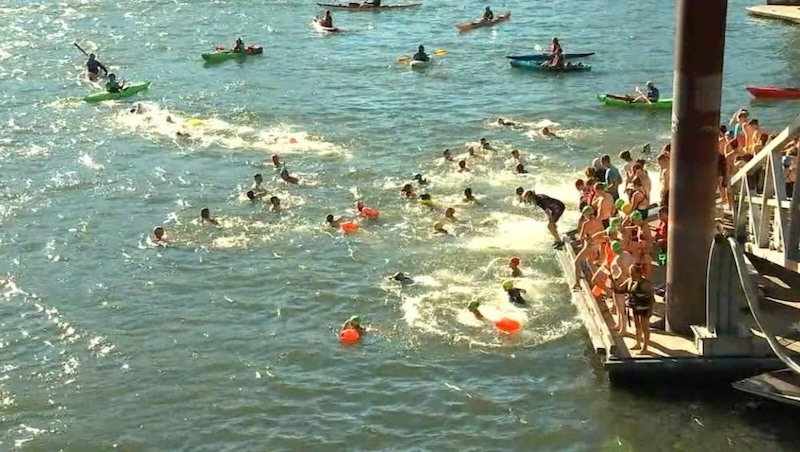Lots of people in swimming caps jumping into the river in Portland, Oregon.