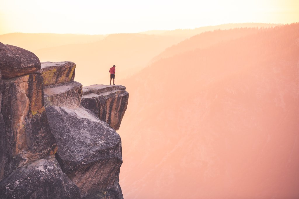 A man stands on the edge of Taft Point in Yosemite Naitonal Park, far above the ground below