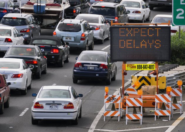 Cars wait in traffic next to a sign that reads "Expect Delays."