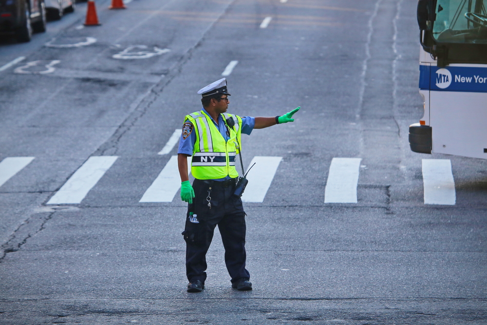 A traffic control officer holds out his hand indicating to drivers to wait.