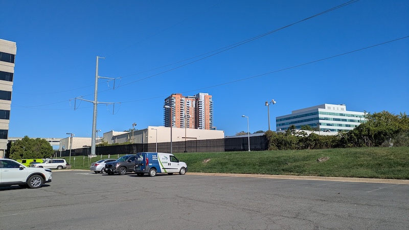 View of two tall buildings from Tysons Corner bike path across asphalt parking lot.