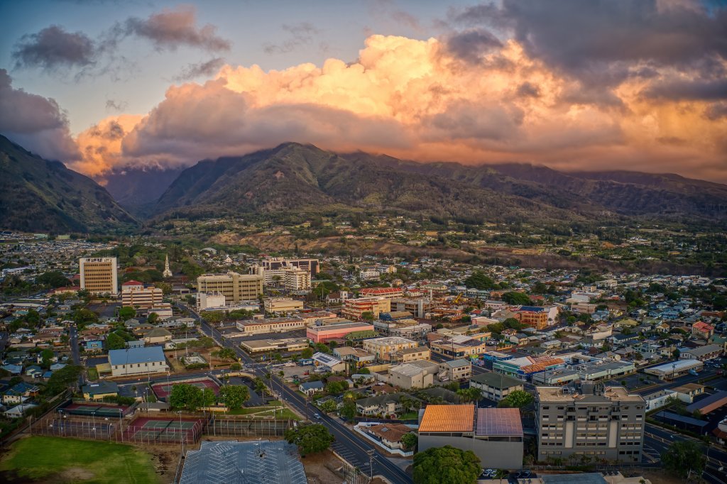 An aerial shot of the city of Wailuku, Maui, with lush green mountains in the background.