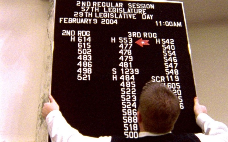 Man putting up board with schedule for city government meetings.