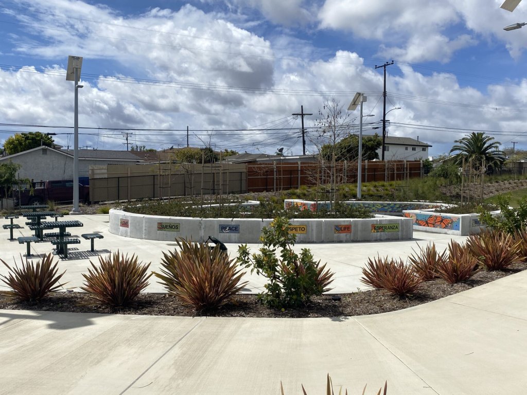 A beautifl park space with landscaping and seating area surrounded by residential homes.