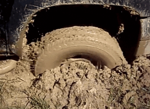 GIF of car tire spinning, stuck in mud.