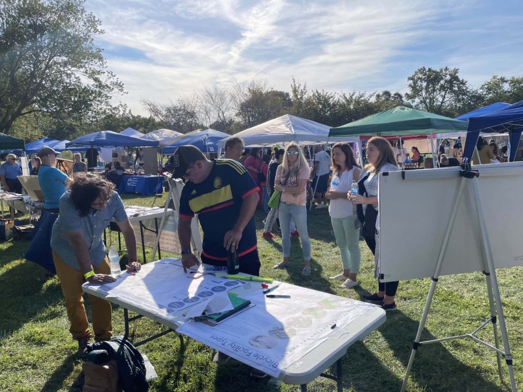 People discuss the future of bicycle facilities at a community fair at a park.