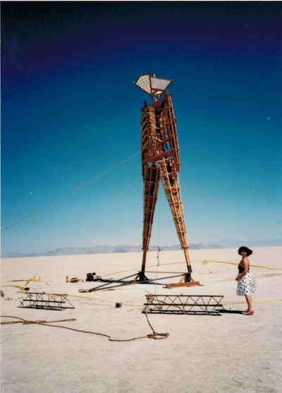P Segal in a black and white polka dot dress stnading next to The Man at her first Burning Man event.