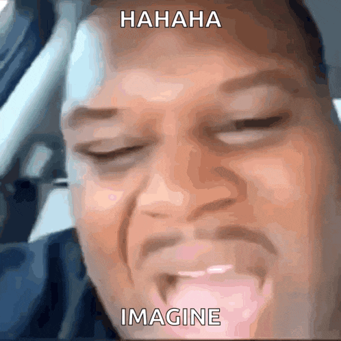 GIF of Black man in car lauging and glancing out the window.