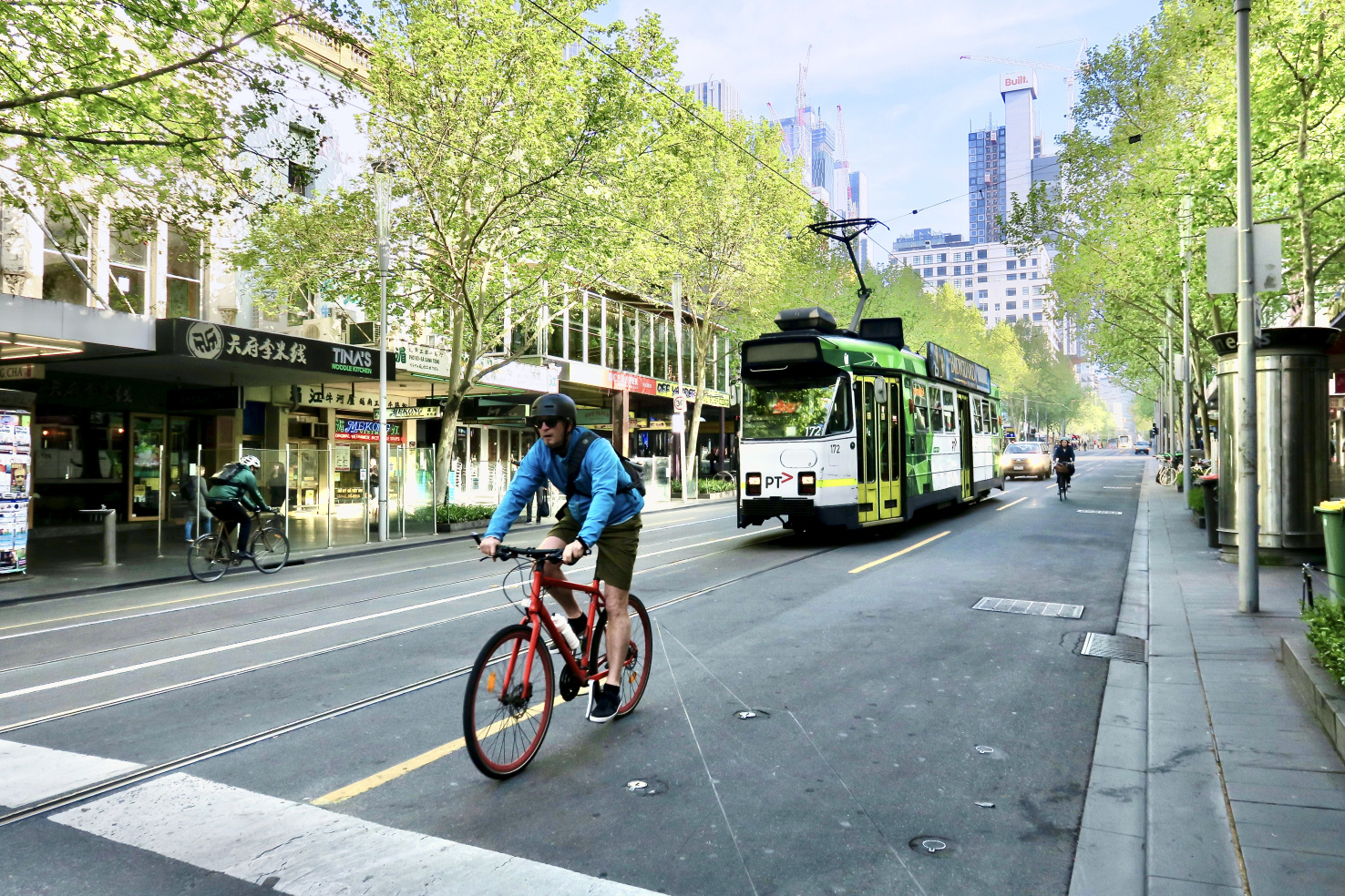 A cyclist rides in front of a street tram