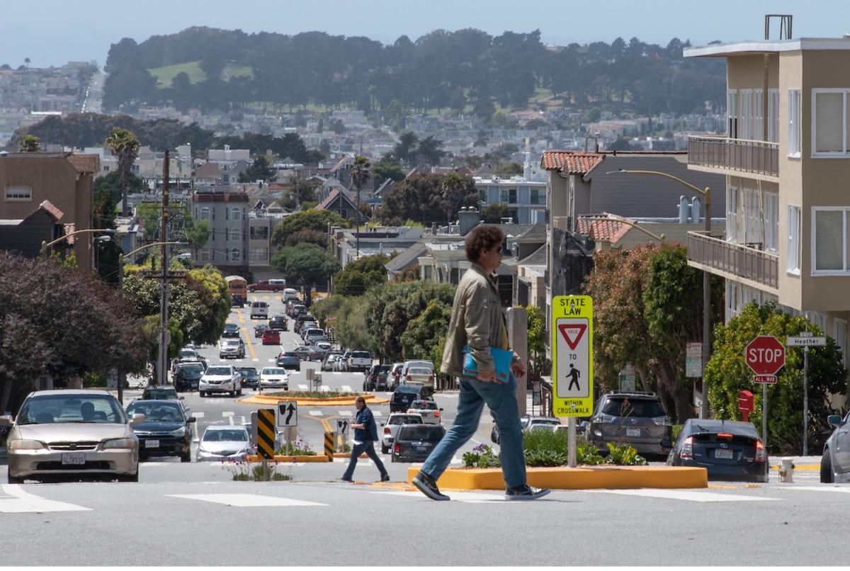 Person walking across street in San Francisco with pedestrian island.