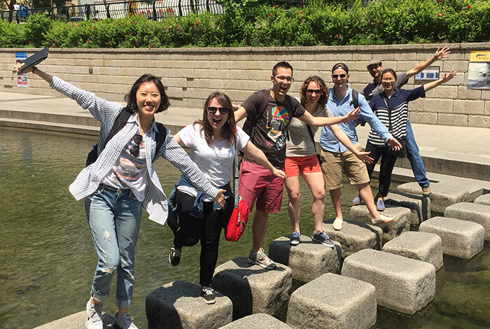 Students balancing on one foot on man made square stones with their arms out