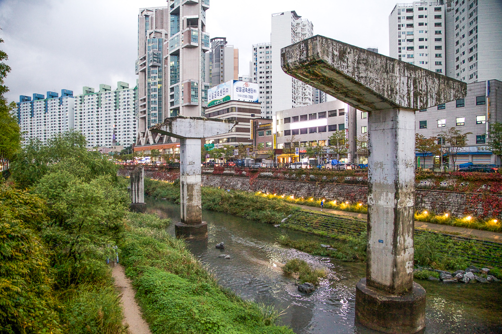 Pillars from a demolished freeway are standing above an urban waterway in Seoul, Korea.