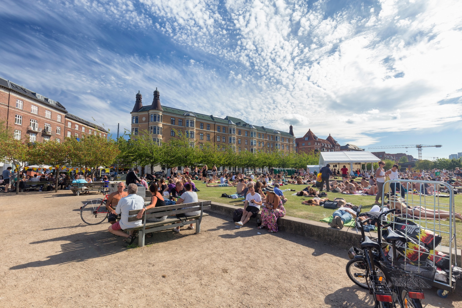 Public park in Copenhgen, Denmark with many people sitting and lying on green lawn.
