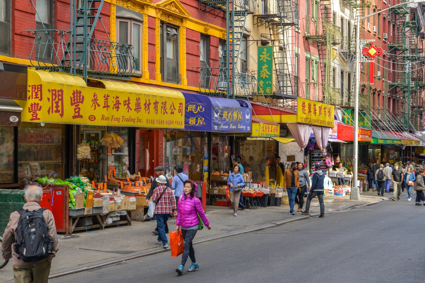 Street scene in New York City's Chinatown with people walking and business signs in Chinese.