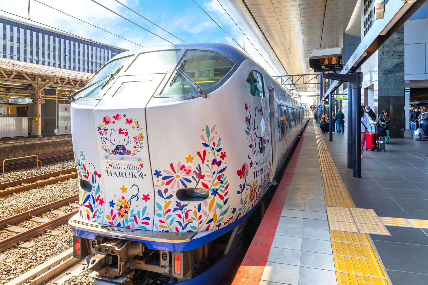 A Hello Kitty-themed train operated by JR West with Hello Kitty iconography and colorful flowers.