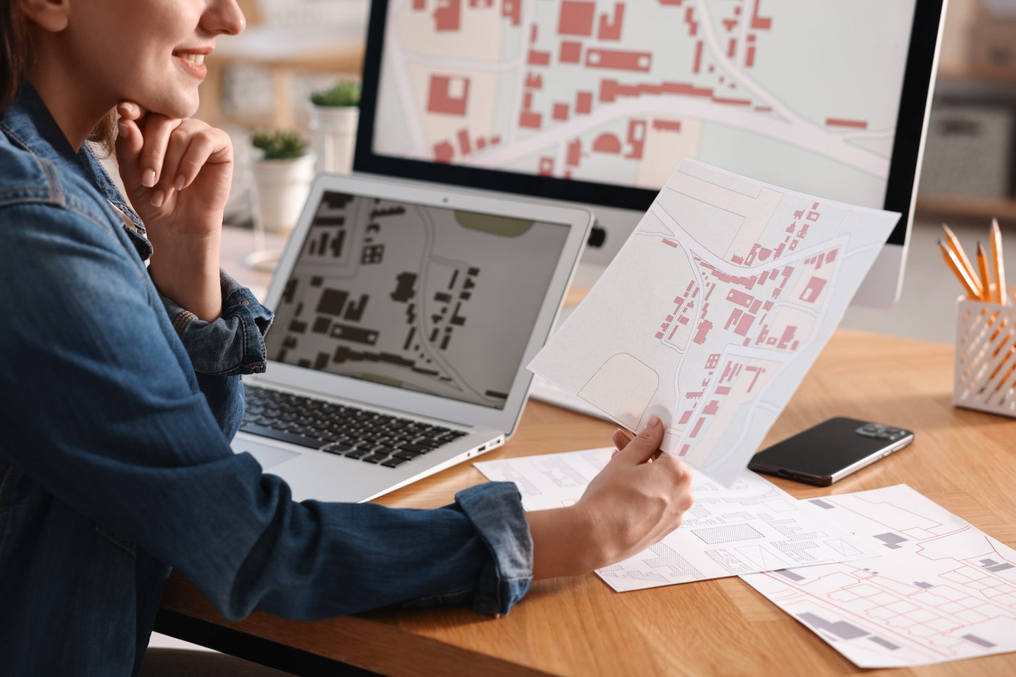 Person looking at printed zoning maps and laptop withsame maps pulled up.