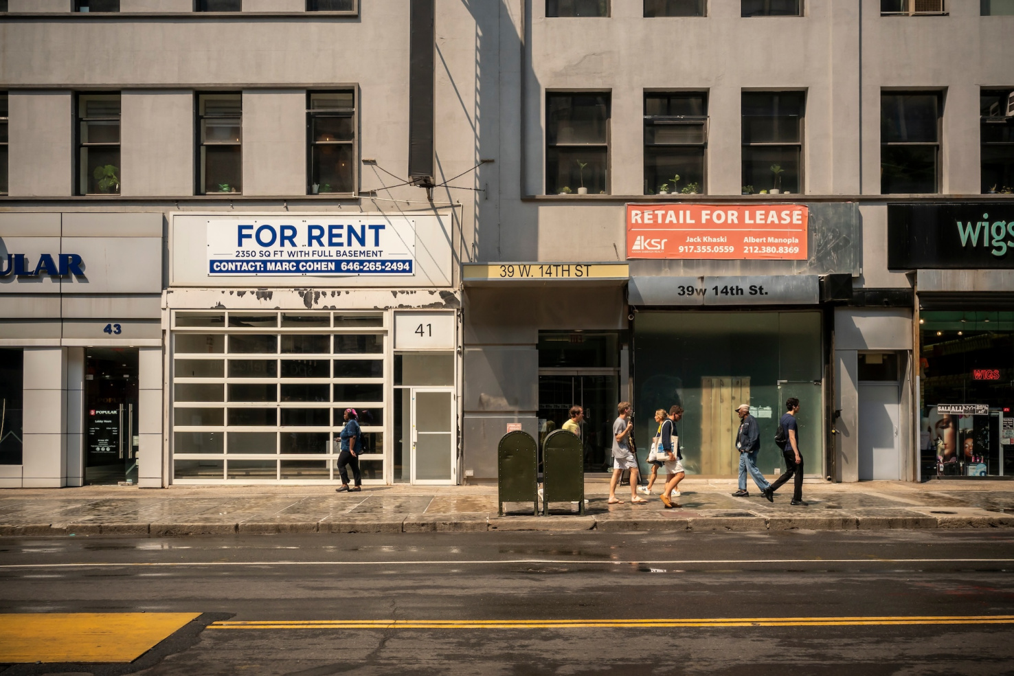 Vacant storefronts with banners advertising space in New York City with people walking on sidewalk.